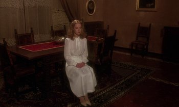 Movie still from “La Cage aux Folles” (1978), directed by Édouard Molinaro – A woman in a white dress sitting on a chair; Wide shot, High angle