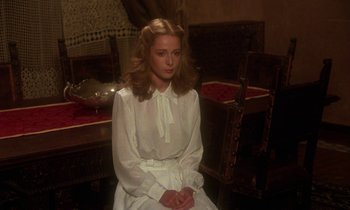Movie still from “La Cage aux Folles” (1978), directed by Édouard Molinaro – A woman in a white dress sitting on a chair; Medium shot, Over the shoulder angle
