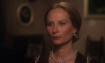 Movie still from “La Cage aux Folles” (1978), directed by Édouard Molinaro – A woman wearing a pearl necklace and a black dress; Close Up shot, Over the shoulder angle