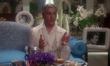Movie still from “La Cage aux Folles” (1978), directed by Édouard Molinaro – A man sitting at a table with a plate of food in front of him; Medium shot, Over the shoulder angle