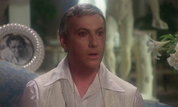 Movie still from “La Cage aux Folles” (1978), directed by Édouard Molinaro – A person wearing a white shirt; Close Up shot, Over the shoulder angle