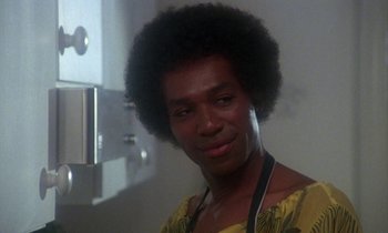 Movie still from “La Cage aux Folles” (1978), directed by Édouard Molinaro – A man with a large afro is smiling for the camera; Close Up shot, Low angle