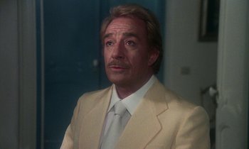 Movie still from “La Cage aux Folles” (1978), directed by Édouard Molinaro – A person wearing a suit and tie; Close Up shot, Low angle