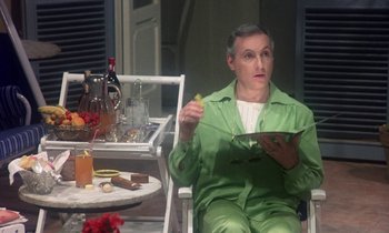Movie still from “La Cage aux Folles” (1978), directed by Édouard Molinaro – An older man sitting at a table with a plate of food in front of him; Medium shot, High angle