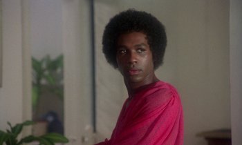 Movie still from “La Cage aux Folles” (1978), directed by Édouard Molinaro – A man in a pink shirt is looking at the camera; Close Up shot, Low angle