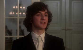 Movie still from “La Cage aux Folles” (1978), directed by Édouard Molinaro – A man in a suit and tie standing in front of a window; Close Up shot, Low angle