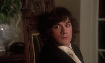Movie still from “La Cage aux Folles” (1978), directed by Édouard Molinaro – A man in a suit sitting in a wooden chair; Close Up shot, High angle