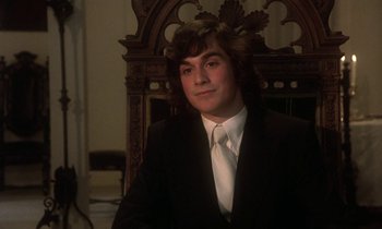 Movie still from “La Cage aux Folles” (1978), directed by Édouard Molinaro – A man in a suit sitting in a chair; Close Up shot, Low angle