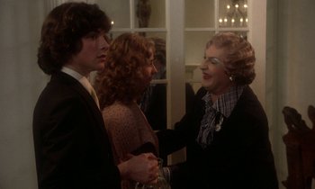 Movie still from “La Cage aux Folles” (1978), directed by Édouard Molinaro – Two women and a man shaking hands at a party; Medium shot, Over the shoulder angle