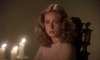 Movie still from “La Cage aux Folles” (1978), directed by Édouard Molinaro – A woman with long blonde curly hair wearing a pink sweater; Close Up shot, Over the shoulder angle