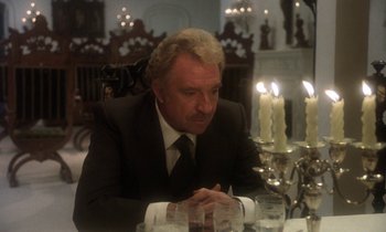 Movie still from “La Cage aux Folles” (1978), directed by Édouard Molinaro – A man in a suit sitting at a dinner table; Medium shot, Over the shoulder angle