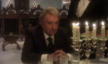Movie still from “La Cage aux Folles” (1978), directed by Édouard Molinaro – An older man sitting at a dinner table with candles; Close Up shot, Over the shoulder angle