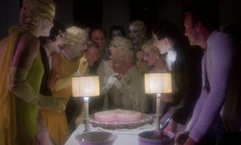 Movie still from “La Cage aux Folles” (1978), directed by Édouard Molinaro – A group of people standing around a cake; Wide shot, Overhead angle
