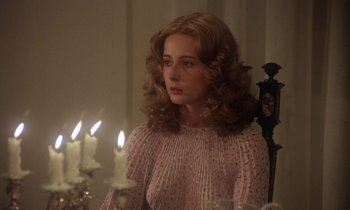 Movie still from “La Cage aux Folles” (1978), directed by Édouard Molinaro – A woman sitting in front of candles in a room; Close Up shot, Over the shoulder angle