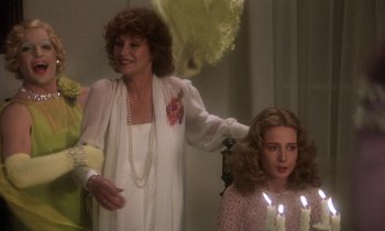 Movie still from “La Cage aux Folles” (1978), directed by Édouard Molinaro – A woman standing next to a young girl with candles; Medium shot, Over the shoulder angle