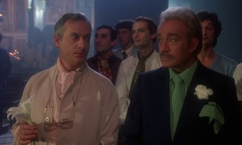 Movie still from “La Cage aux Folles” (1978), directed by Édouard Molinaro – A group of men standing next to each other in a room; Medium shot, Over the shoulder angle