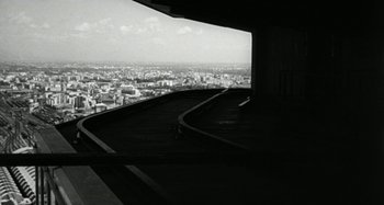 Movie still from “La Notte” (1961), directed by Michelangelo Antonioni – A black and white photo of a train track with a city in the background; Extreme Wide shot, Low angle