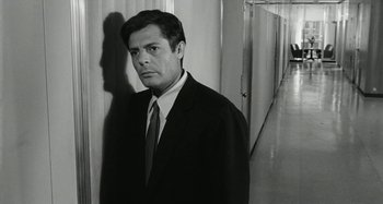 Movie still from “La Notte” (1961), directed by Michelangelo Antonioni – Black and white photograph of a man wearing a suit and tie; Medium shot, High angle
