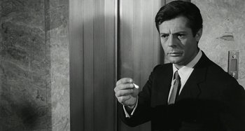 Movie still from “La Notte” (1961), directed by Michelangelo Antonioni – A black and white photo of a man smoking a cigarette; Close Up shot, Low angle