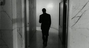 Movie still from “La Notte” (1961), directed by Michelangelo Antonioni – A man in a suit walking through a hallway; Wide shot, Low angle