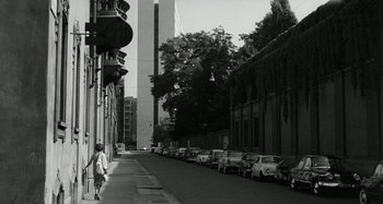 Movie still from “La Notte” (1961), directed by Michelangelo Antonioni – A black - and - white photo of a city street with parked cars; Extreme Wide shot, Low angle