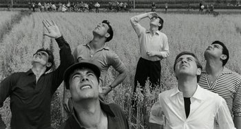 Movie still from “La Notte” (1961), directed by Michelangelo Antonioni – A group of men standing in the middle of a field; Medium shot, Low angle
