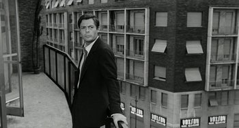 Movie still from “La Notte” (1961), directed by Michelangelo Antonioni – Black and white photograph of a man in a suit and tie; Medium shot, Low angle
