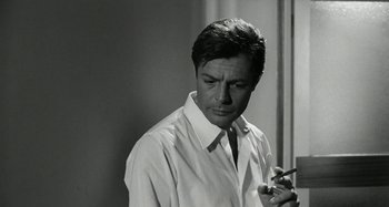 Movie still from “La Notte” (1961), directed by Michelangelo Antonioni – A black - and - white photo of a man smoking a cigarette; Close Up shot, Low angle