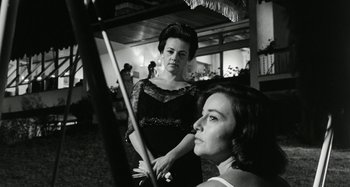 Movie still from “La Notte” (1961), directed by Michelangelo Antonioni – Two women in black and white holding a pool cue; Medium shot, Low angle