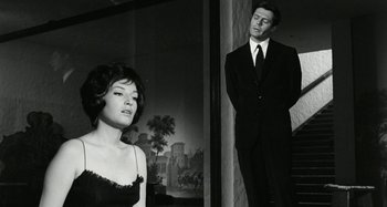 Movie still from “La Notte” (1961), directed by Michelangelo Antonioni – A man and a woman standing next to each other in front of a painting; Medium shot, Low angle