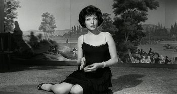 Movie still from “La Notte” (1961), directed by Michelangelo Antonioni – A woman sitting on the ground in front of a painting; Medium shot, Low angle