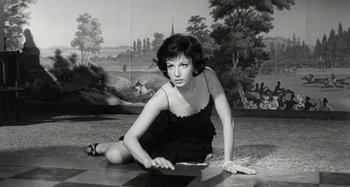 Movie still from “La Notte” (1961), directed by Michelangelo Antonioni – A woman in a black dress laying on the ground; Medium shot, High angle