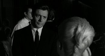 Movie still from “La Notte” (1961), directed by Michelangelo Antonioni – A black and white photo of a man wearing a suit and tie; Close Up shot, Over the shoulder angle