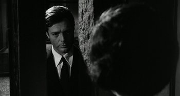 Movie still from “La Notte” (1961), directed by Michelangelo Antonioni – A black and white photo of a man in a suit and tie; Close Up shot, Over the shoulder angle