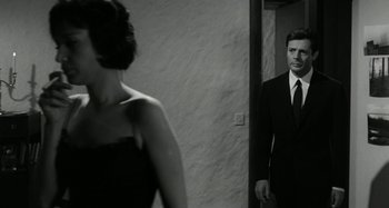 Movie still from “La Notte” (1961), directed by Michelangelo Antonioni – A man and a woman are standing in front of a mirror; Medium shot, Over the shoulder angle