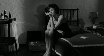 Movie still from “La Notte” (1961), directed by Michelangelo Antonioni – A black and white photo of a woman smoking a cigarette; Medium shot, Low angle