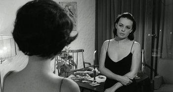 Movie still from “La Notte” (1961), directed by Michelangelo Antonioni – A woman sitting at a table in front of a mirror; Medium shot, Over the shoulder angle
