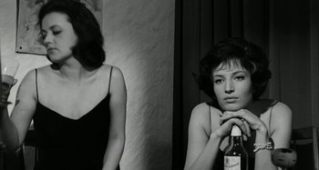 Movie still from “La Notte” (1961), directed by Michelangelo Antonioni – Two women are posing for a picture with a bottle of wine; Close Up shot, Over the shoulder angle