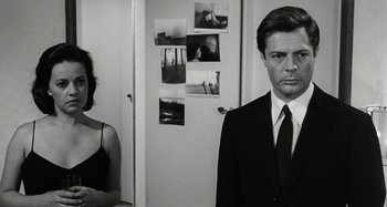 Movie still from “La Notte” (1961), directed by Michelangelo Antonioni – A woman standing next to a man in front of a door; Medium shot, Over the shoulder angle