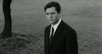 Movie still from “La Notte” (1961), directed by Michelangelo Antonioni – Black and white photograph of a man wearing a suit and tie; Close Up shot, Low angle