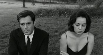 Movie still from “La Notte” (1961), directed by Michelangelo Antonioni – A man and a woman sitting next to each other in the grass; Close Up shot, High angle