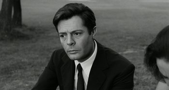 Movie still from “La Notte” (1961), directed by Michelangelo Antonioni – Black and white photograph of a man wearing a suit and tie; Close Up shot, Low angle