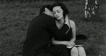 Movie still from “La Notte” (1961), directed by Michelangelo Antonioni – A man and a woman sitting on the grass; Medium shot, High angle