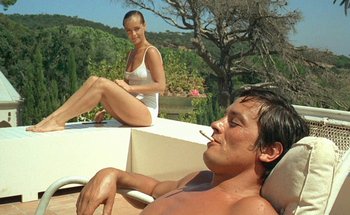 Movie still from “The Swimming Pool” (1969), directed by Jacques Deray – A man and a woman sitting on a ledge; Medium shot, Low angle