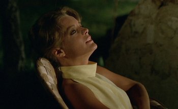Movie still from “The Swimming Pool” (1969), directed by Jacques Deray – A woman sitting in a chair with her eyes closed; Medium shot, Low angle