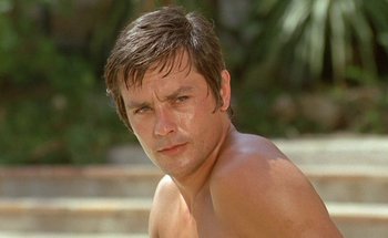 Movie still from “The Swimming Pool” (1969), directed by Jacques Deray – A shirtless man with no shirt on looking at the camera; Close Up shot, Low angle