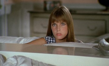 Movie still from “The Swimming Pool” (1969), directed by Jacques Deray – A woman sitting on a bed looking at the camera; Close Up shot, Low angle