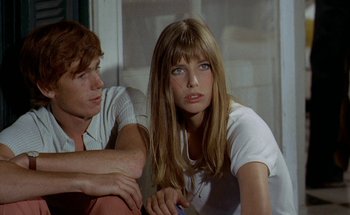 Movie still from “The Swimming Pool” (1969), directed by Jacques Deray – A woman sitting next to a man in a white shirt; Close Up shot, High angle