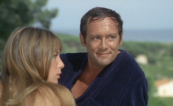 Movie still from “The Swimming Pool” (1969), directed by Jacques Deray – A man and a woman in a blue robe; Close Up shot, Low angle