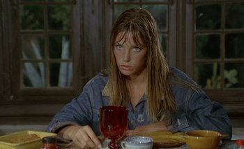 Movie still from “The Swimming Pool” (1969), directed by Jacques Deray – A woman sitting at a table with a glass of red wine; Close Up shot, High angle